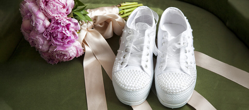 Białe sneakersy damskie do ślubu obok bukietu kwiatów