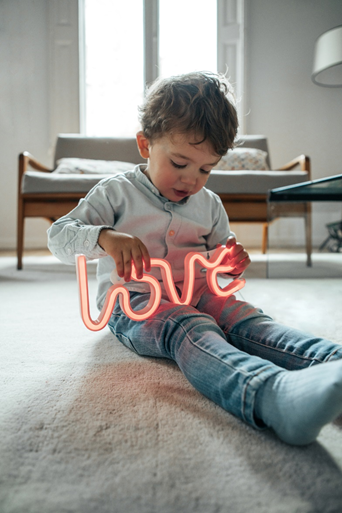 Mały chłopiec bawiący się neonowym napisem love