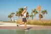 Młody mężczyzna uprawiający jogging w męskich butach sportowych, w tle palmy i plaża