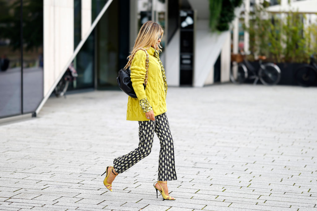 Moteris, dėvinti geltoną megztinį ir geltonas basutes