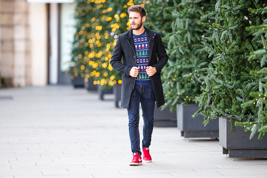 mężczyzna w świątecznym swetrze i czerwonych sneakersach Nike